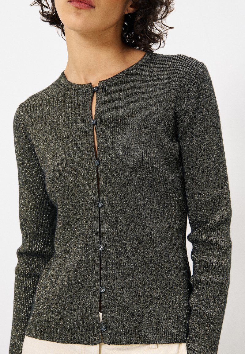 Dunkelgrüne, gerippte Strickjacke mit rundem Halsausschnitt, vorderer Knopfleiste und metallischen Fäden. Lange Ärmel und figurbetonte Passform.