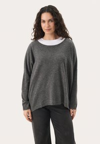 Dark grey knitted sweater with a loose fit, wide neckline, and long sleeves, paired with black jeans. Soft texture, minimal design.