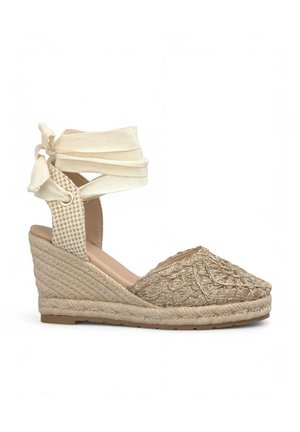 Sandalia de cuña de esparto beige con suela de yute trenzado, bordado intrincado en la puntera y cintas de tela ajustables en el tobillo. Panel superior texturizado.