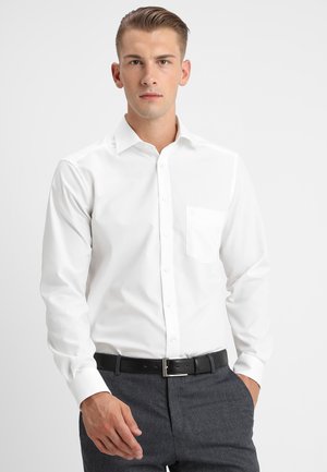 White long-sleeve button-up shirt with a single chest pocket. Made of cotton, featuring a classic collar and smooth texture. Paired with dark trousers.