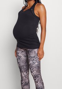 Canottiera nera a costine con scollatura rotonda e design a schiena scoperta, abbinata a leggings grigi con un sottile motivo a stampa leopardata.