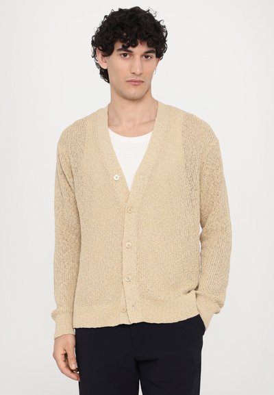 Beige strikket cardigan med V-hals, fem knapper og ribbestrikkede mansjetter og kant. Den teksturerte stoffet gir et uformelt utseende.