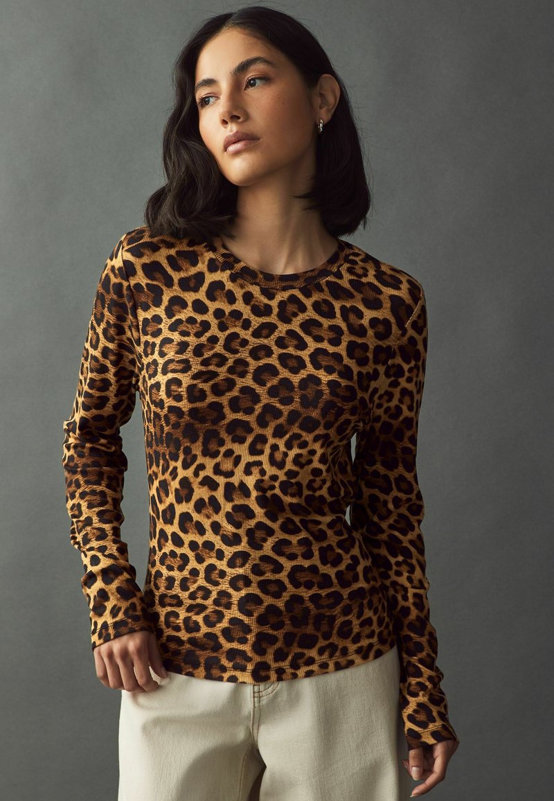 Top a maniche lunghe con stampa leopardata realizzato in tessuto a costine, caratterizzato da scollatura rotonda, forma aderente e macchie nere a contrasto su uno sfondo beige.
