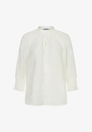 White long-sleeve blouse with gathered neckline, keyhole front with button closure, and smocked ruffle cuffs.