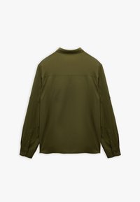 Oliwkowa, długosleeve shirtka, wykonana z gładkiego materiału. Posiada kołnierzyk, mankiety zapinane na guziki oraz panel yoke z tyłu.