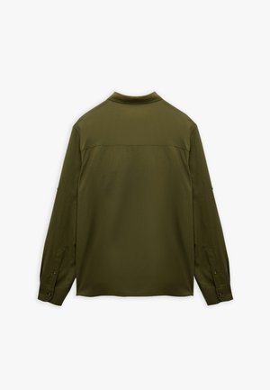 Camicia a maniche lunghe verde oliva, realizzata in un tessuto liscio. Presenta un colletto, polsini con bottoni e un pannello yoke sul retro.