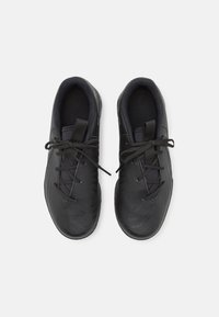 Baskets noires de sport avec une surface texturée, un bout rond et des lacets en tissu lisse ; design minimaliste et intérieur rembourré pour le confort.