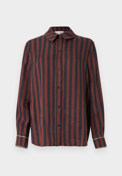 Hosszú ujjú gombos ing, amely piros és sötétkék függőleges csíkokkal, galléros nyakkivágással és kontrasztos részletekkel a mandzsettán.
