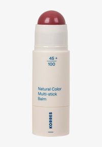 Baume multi-usage couleur naturelle dans un tube blanc avec du baume rouge exposé, étiqueté "45+ / 100" et marqué "KORRES" en texte bleu.