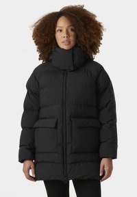 Melnā pūkaina jaka ar augstu apkakli, priekšā rāvējslēdzēju un divām lielām vāciņu kabatām. Raksturota ar šūtu dizainu un mīkstu, izolētu tekstūru.