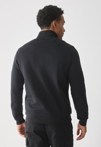 Zwarte sweatshirt met lange mouwen, hoge kraag en geribbelde manchetten, met een gladde stof en een aansluitend ontwerp.