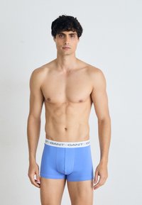 Blaue Baumwoll-Boxershorts mit einem weißen Bund, auf dem das Logo "GANT" aufgedruckt ist. Figurbetontes Design mit glatter Textur und ohne sichtbare Muster.