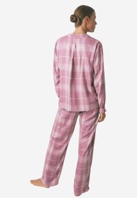 Lyserøde ternede pyjamas i blødt stof, der har en knaplukket skjorte og bukser med elastisk talje, lange ærmer og en afslappet pasform.