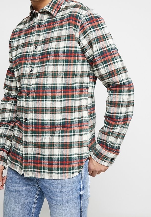 Karo-Flanellhemd in Weiß-, Grün- und Rottönen mit Knopfleiste, spitzem Kragen und langen Ärmeln, getragen über blauen Jeans.
