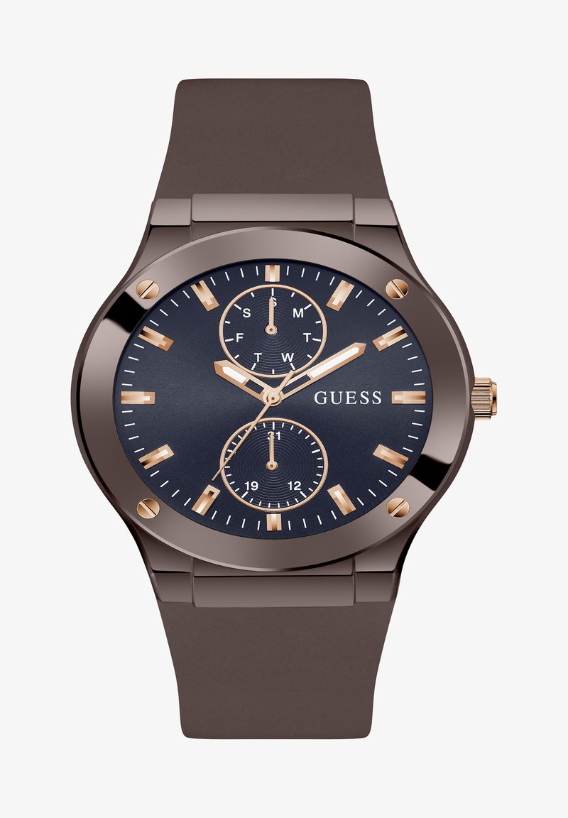 Montre avec un bracelet en silicone marron et un cadran bleu marine. Présente des index horaires dorés, trois sous-cadrans et un boîtier métallique. Nom de la marque affiché.