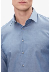 Camicia button-up azzurro chiaro con un motivo testurizzato, con colletto e sei bottoni, con un piccolo logo sul petto.
