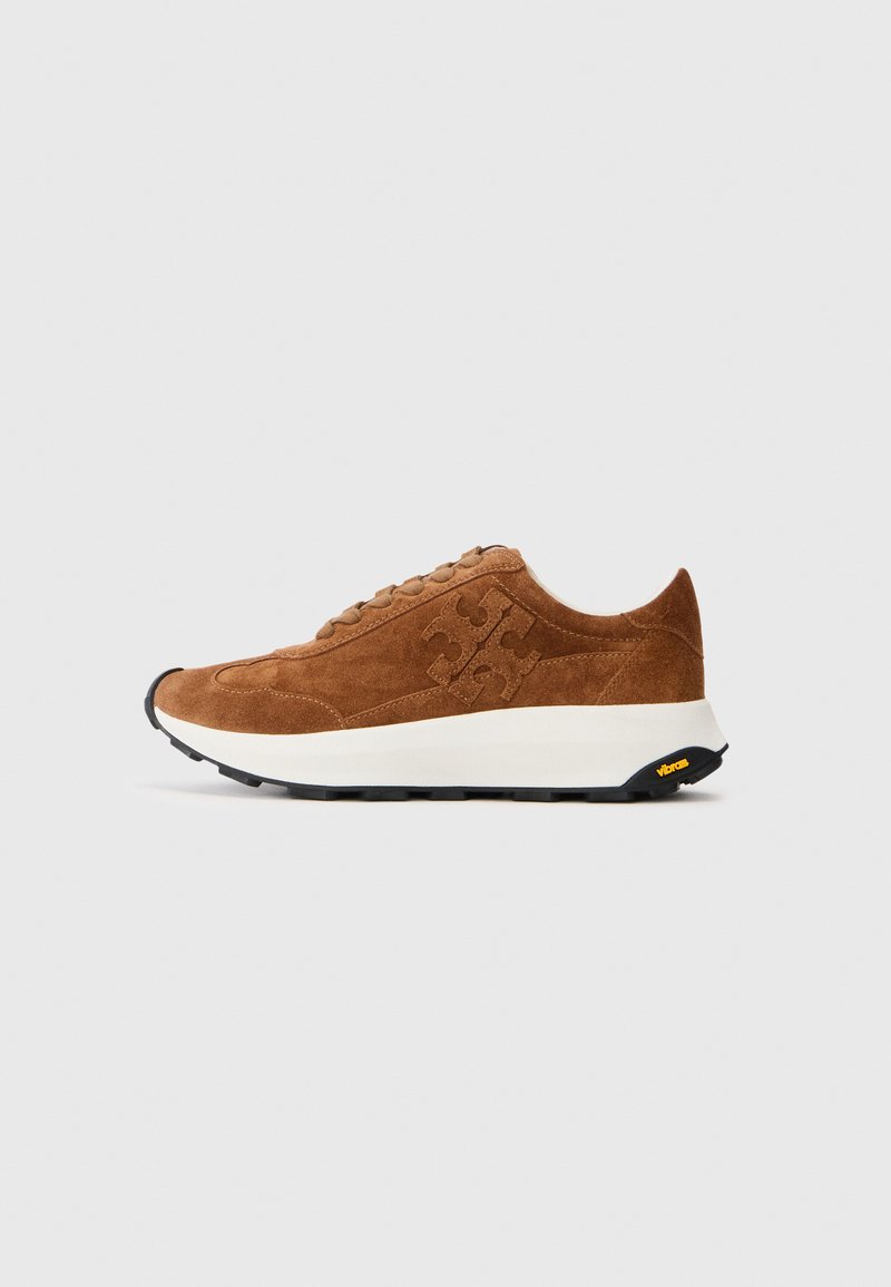 Brown suede sneaker with logo detail, white midsole, black Vibram outsole, and lace-up closure, shown from the side on a plain background.