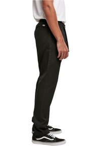 Svarte joggebukser med elastisk midje, sidelommer og smal passform, kombinert med svart og hvitt joggesko.
