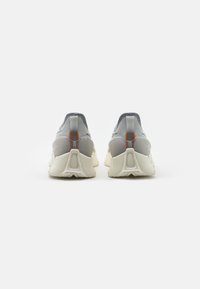 Gray running shoes with a textured upper, contrasting white sole, and orange accent at the heel. Rounded shape, breathable design.