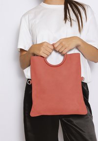 Borsa a tracolla corallo con manico tondo, realizzata in materiale morbido. Presenta dettagli metallici e un design minimalista. La dimensione è moderata.
