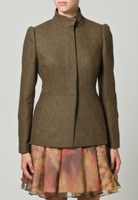 Chaqueta de tweed marrón con un alto cuello, hombros estructurados y un diseño ajustado, combinada con una falda con capas en tonos suaves y cálidos.