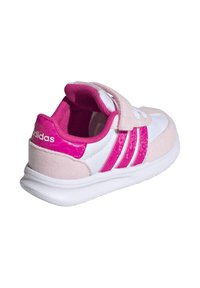 Zapatilla deportiva rosa y blanca con cinta de velcro, materiales de ante y sintéticos, tres franjas rosas y una suela blanca acolchada.