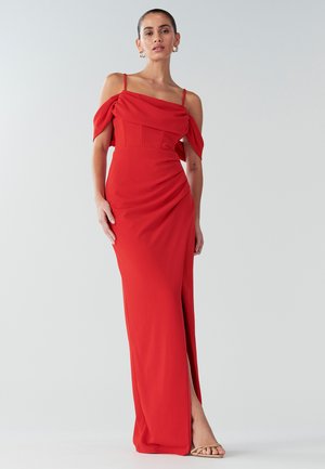 Vestido rojo hasta el suelo con diseño asimétrico en los hombros, abertura lateral y mangas drapeadas. Confeccionado en una tela suave con un corsé ajustado.