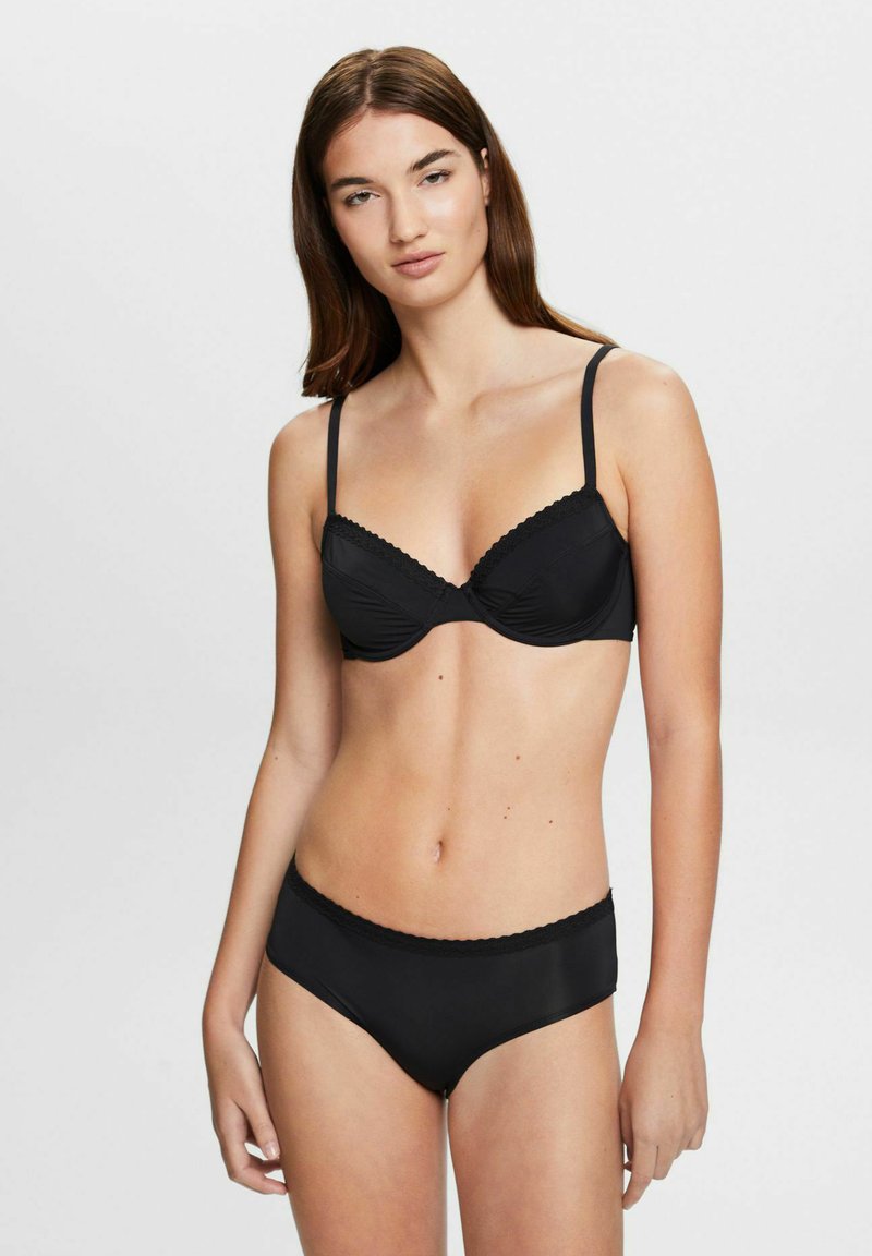 Schwarzes Lingerie-Set, das einen kabellosen BH und passende hochtaillierte Panties umfasst. Enthält zarte Spitzenverzierungen und eine glatte Stoffstruktur.