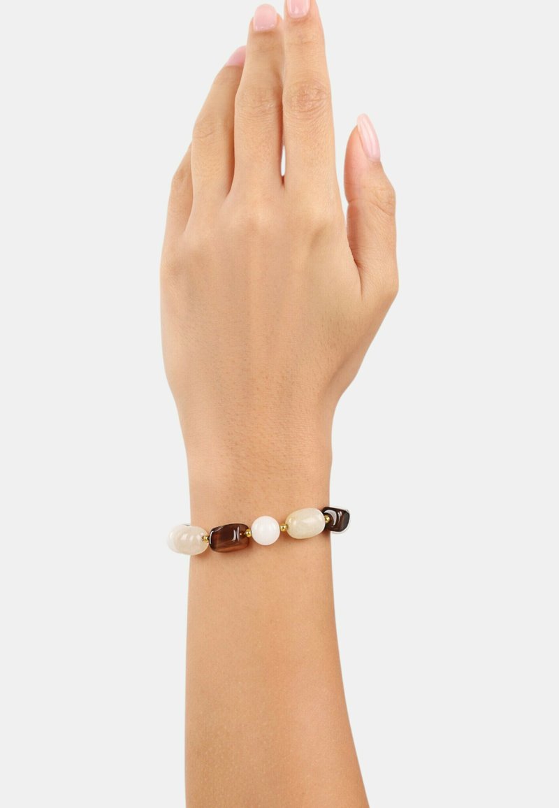 Bracciale di perline con una miscela di pietre marroni, bianche e color crema con accenti dorati, esposto su una mano. Texture liscia e lucida.