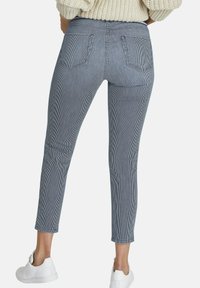 Blauwe en witte gestreepte enkel-lange broeken met een slim fit ontwerp, vier zakken en een gladde textuur, gecombineerd met witte schoenen.