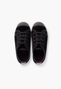 Un paio di sneakers in tela nera con punte in gomma e lacci, viste dall'alto su uno sfondo bianco.