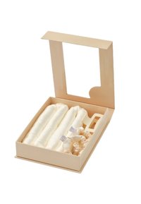 Pudełko z trzema zwiniętymi białymi tkaninami i dwoma kremowymi gumkami do włosów, wyeksponowane z otwartą pokrywą wyposażoną w prostokątne okienko.