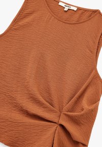 Rostvärgad ärmlös topp i en strukturerad tyg, med en samlad tvistdetalj på sidan och en rund halsringning.