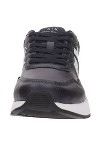 Scarpe sportive blu navy con tomaia in pelle testurizzata, lacci neri, accenti bianchi e una suola in gomma con motivo. Design semplice, vista frontale.