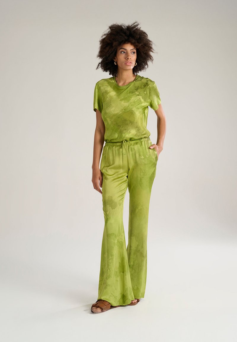 Completo due pezzi verde in satin con top a maniche corte e pantaloni con coulisse. Design fluido con un sottile motivo ad acquerello, caratterizzato da gambe svasate.