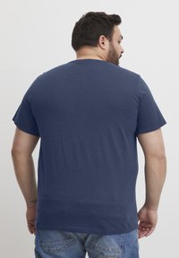 Tamsiai mėlynas trumpomis rankovėmis marškinėliai iš minkštos medvilnės. Paprastas dizainas su apvalia iškirpte ir laisvu siluetu, matomas iš nugaros.