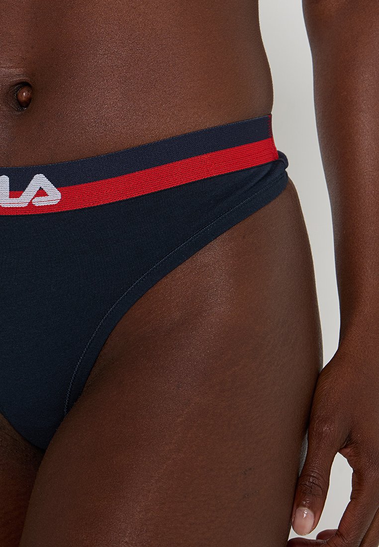 Bas de bikini bleu marine avec une ceinture logo rouge et blanche contrastante. Tissu doux avec une texture lisse, présentant une coupe taille basse.