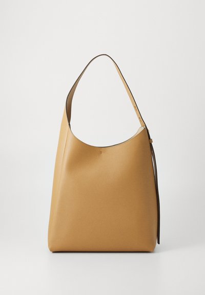 Sac hobo en cuir beige, avec une texture douce et lisse. Il possède une large bandoulière en marron foncé, conçue avec un haut incurvé.