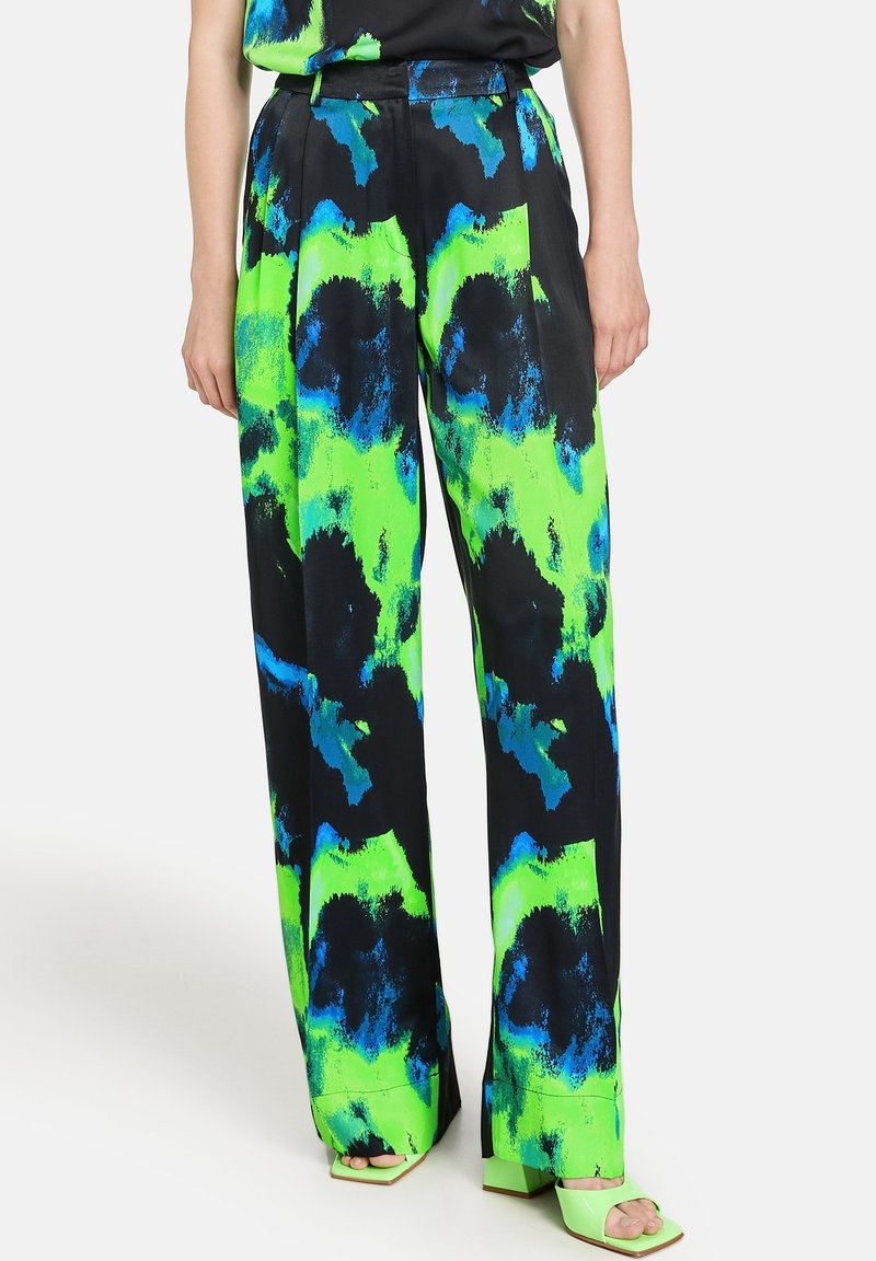 Pantalon large avec un motif abstrait vibrant de vert, bleu et noir ; fabriqué en tissu léger avec une texture lisse, présentant une taille haute.