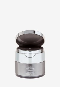 Glas-Nachtcreme-Glas mit einem silbernen Deckel, der einen transparenten dunkelgrauen Boden aufweist. Das Etikett trägt die Aufschrift "SARAH CHAPMAN London Icon Night."