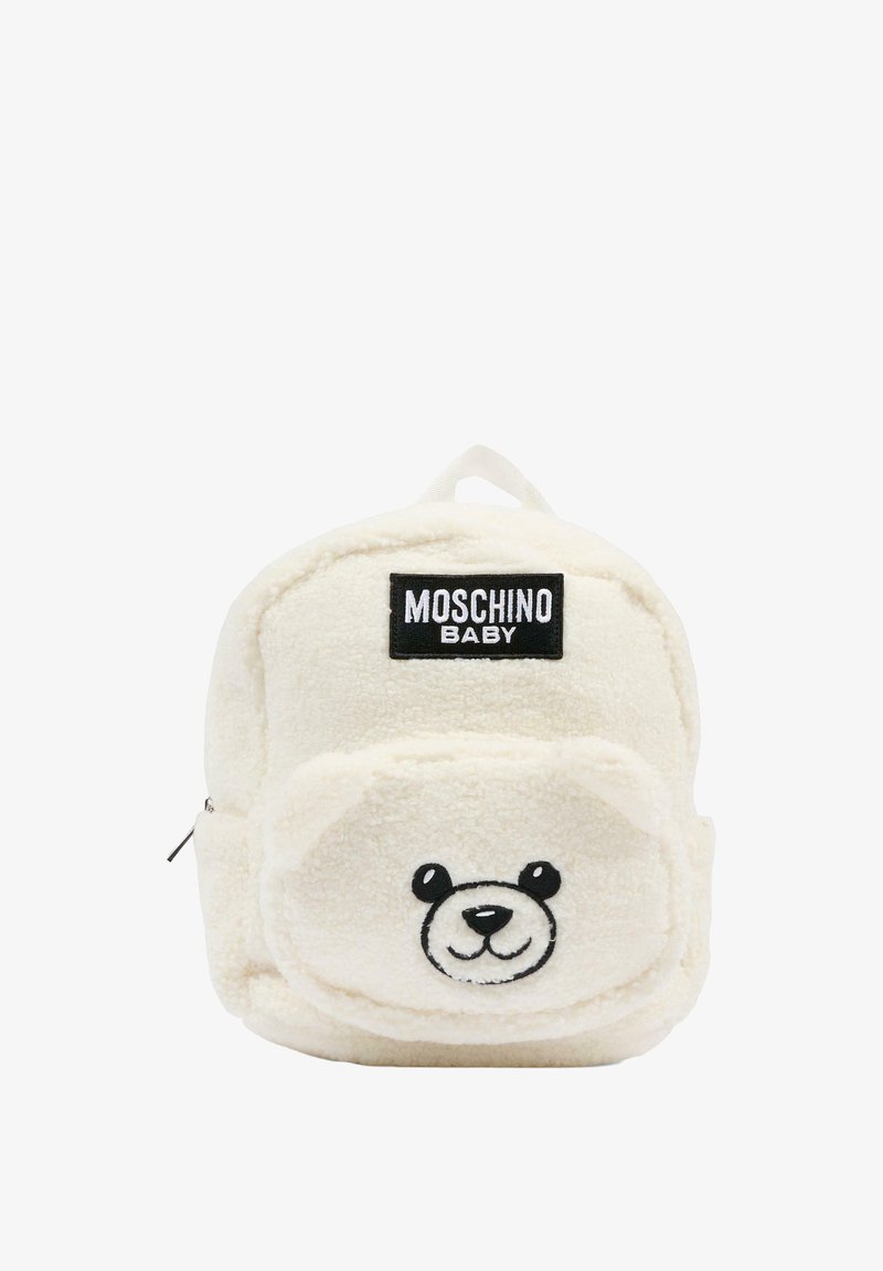 Sac à dos en peluche couleur crème avec un design de visage d'ours, des détails brodés et une poignée supérieure pour le transport. Logo de la marque affiché de manière proéminente.