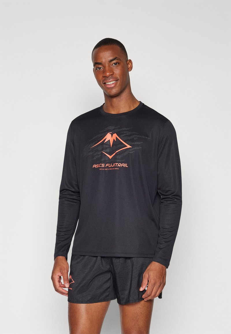 Schwarzes, langärmeliges Sporthemd mit einem orangen Berglogo und Text. Getragen mit schwarzen Shorts, die einen glatten, leichten Stoff präsentieren.
