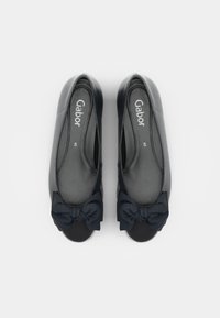 Paire de ballerines noires avec des bouts arrondis et des nœuds en tissu sur le dessus, indiquant la taille 5 et la marque Gabor à l'intérieur.