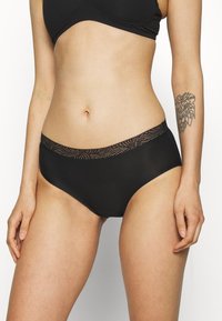 Black high-waisted panties with a sheer lace trim at the waistband, featuring a smooth texture and a classic full-coverage design.