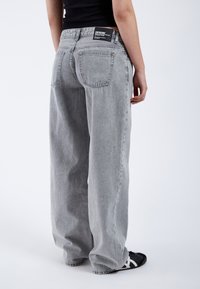 Grijze wijde spijkerbroek met hoge taille, uitgerust met een klassiek vijf-pocket ontwerp en een merkpatch aan de achterkant. De stof heeft een lichte textuur.
