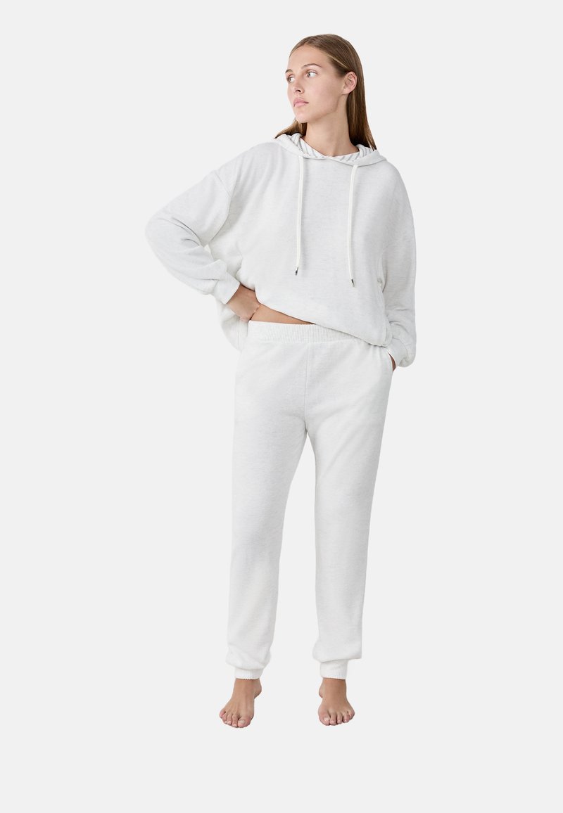 Witte katoenen hoodie met trekkoorden en lange mouwen, gecombineerd met bijpassende sweatpants. Zachte textuur, relaxed fit en omgeslagen enkels.