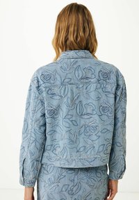 Jasnoniebieska kurtka dżinsowa z haftowanymi kwiatowymi wzorami w ciemniejszych odcieniach, z kołnierzykiem i zapięciem na guziki przy mankietach. Prosty i teksturowany wzór.