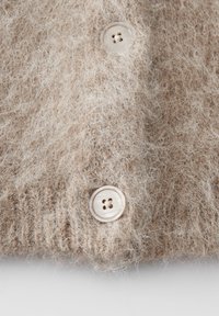 Close-up of beige fuzzy knit fabric with two large, round, light brown buttons sewn on.