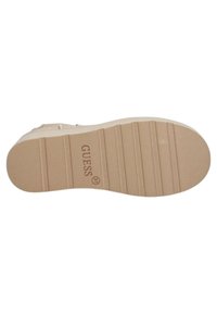 Sole di scarpa in gomma beige con un motivo testurizzato e logo, dotata di scanalature orizzontali per la trazione e un bordo liscio attorno al perimetro.