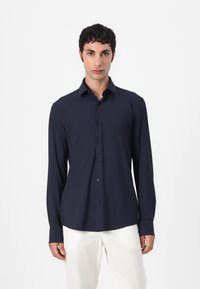 Marineblaues Langarmhemd mit Knopfkragen, aus glattem Stoff gefertigt, mit einer Vorderleiste und dunklen Knöpfen. Einfaches Design.